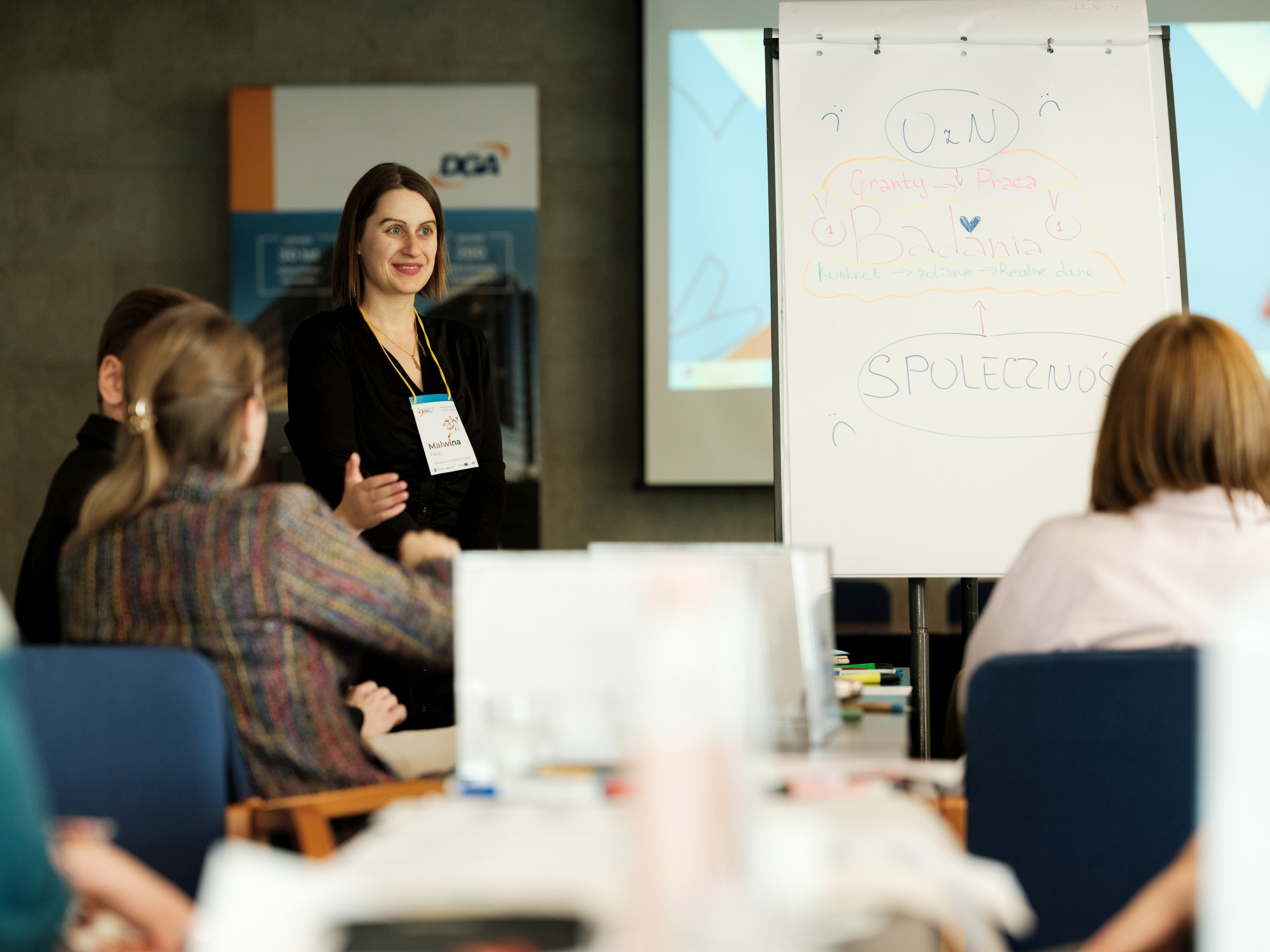 Malwina Faza stoi przed uczestnikami kick-off Inkubatora Wielkich Jutra.